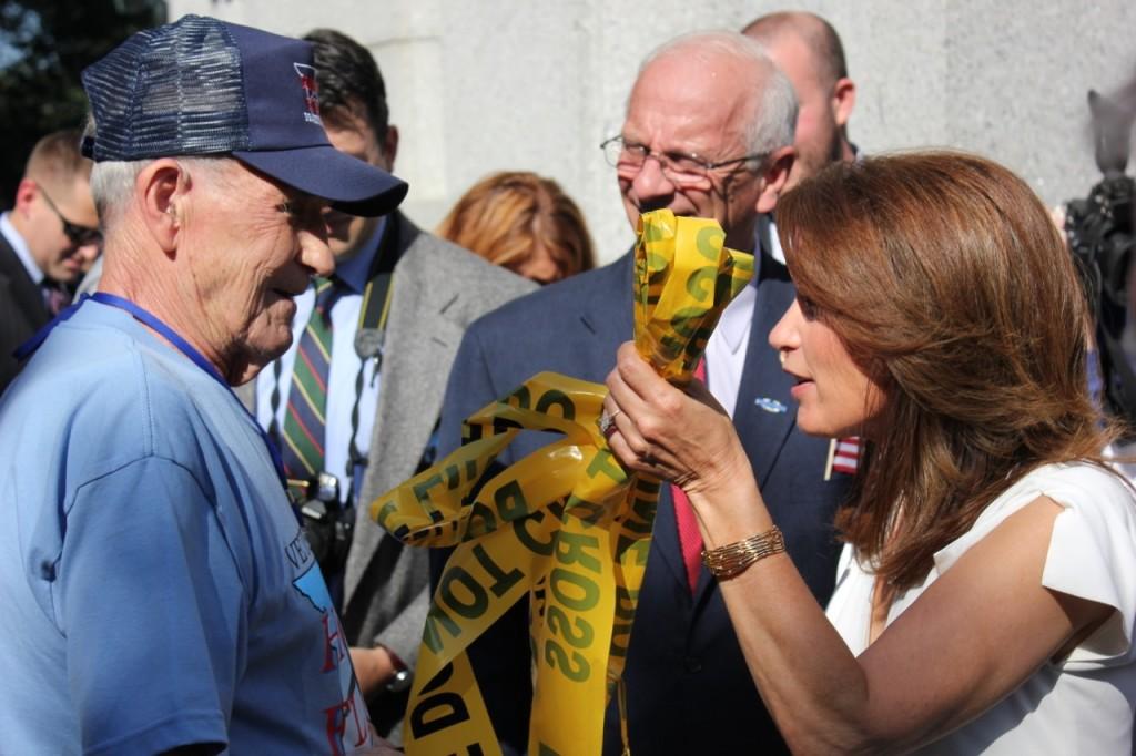 Rep. Michele Bachmann, R-Minn., shows a veteran the “do not cross” tape she tore down to allow the veterans inside the World War II Memorial. The memorial has been barricaded by fences and the tape since the government shutdown started on Tuesday. 