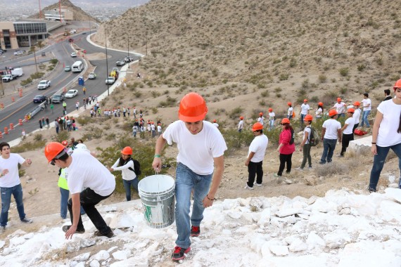 Computer science major Jade Garcia climbs up mountain to dump a bucket of paint. 