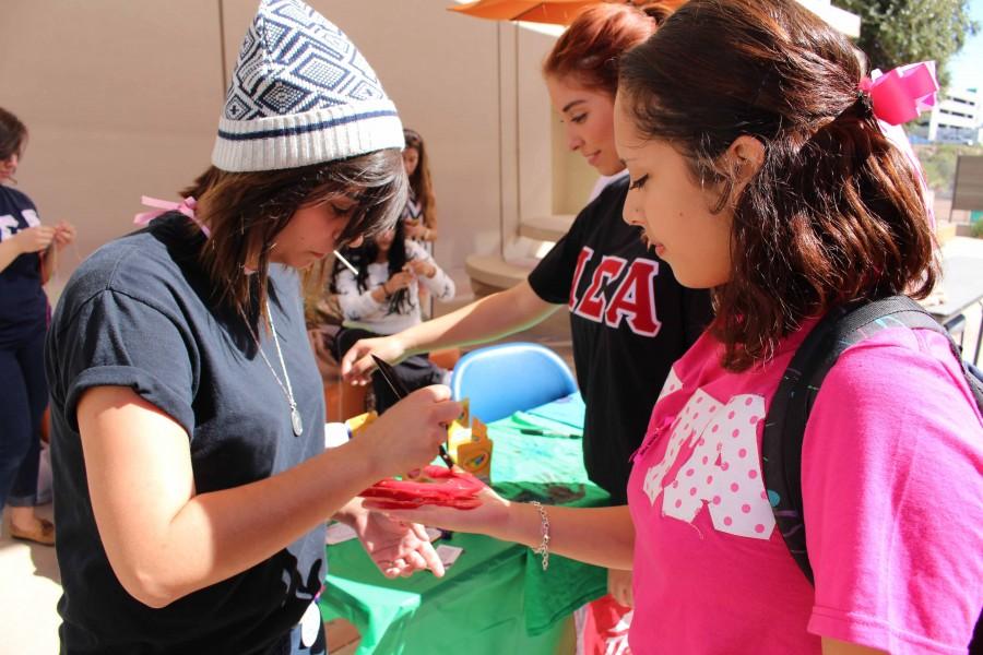 Kaitlyn Mullins paints Alexis Gonzales hand for the banner