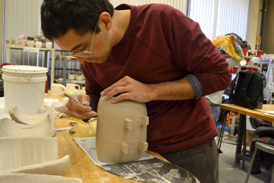 Senior studio art major Alejandro Perea works on a ceramic sushi disk. 