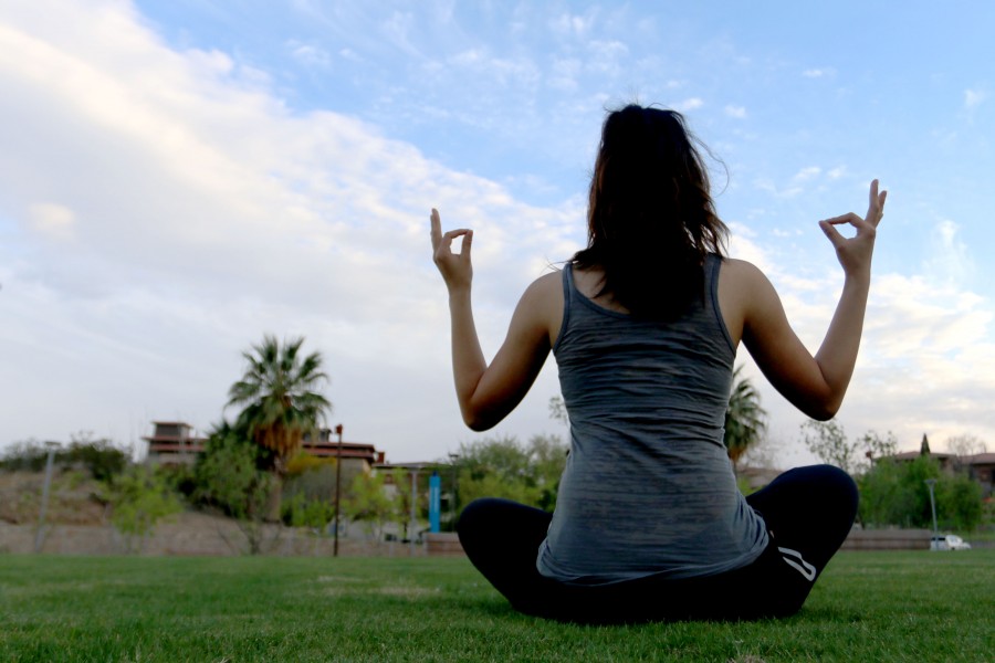 A student meditates on open grass at Centennial Plaza. 