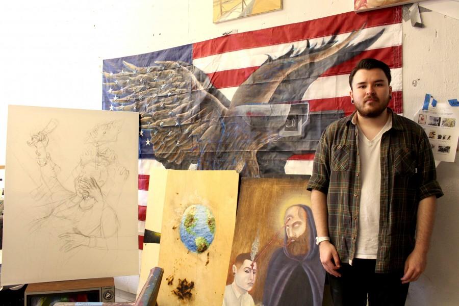 Senior studio art major, Deven Mc Coy, stands infront of his art work at the Fox Fine Arts Center. 