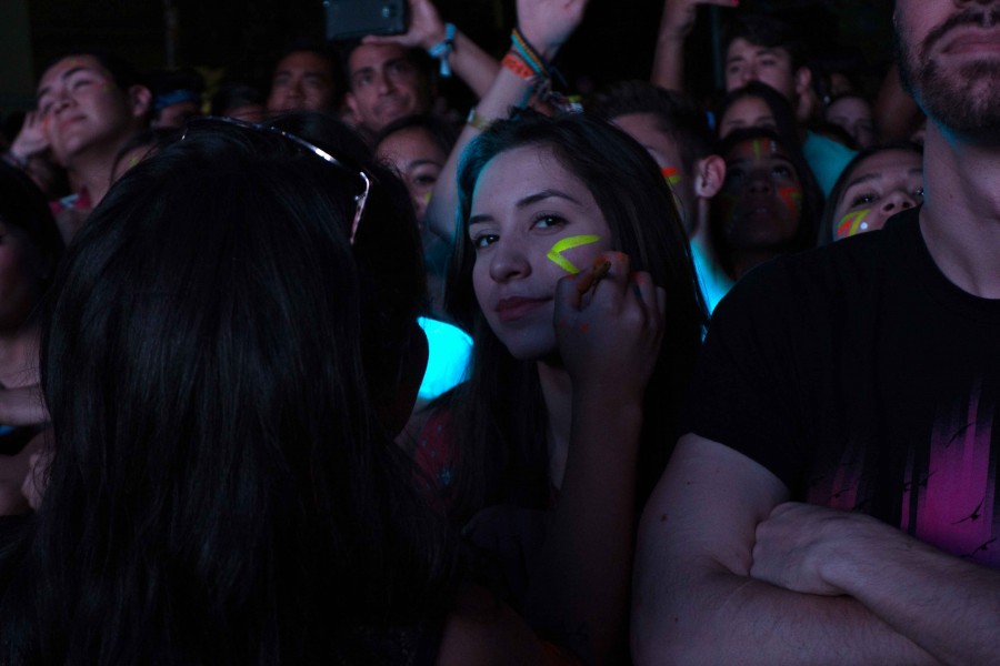 An attendee gets her face painted while watching Robert DeLong.