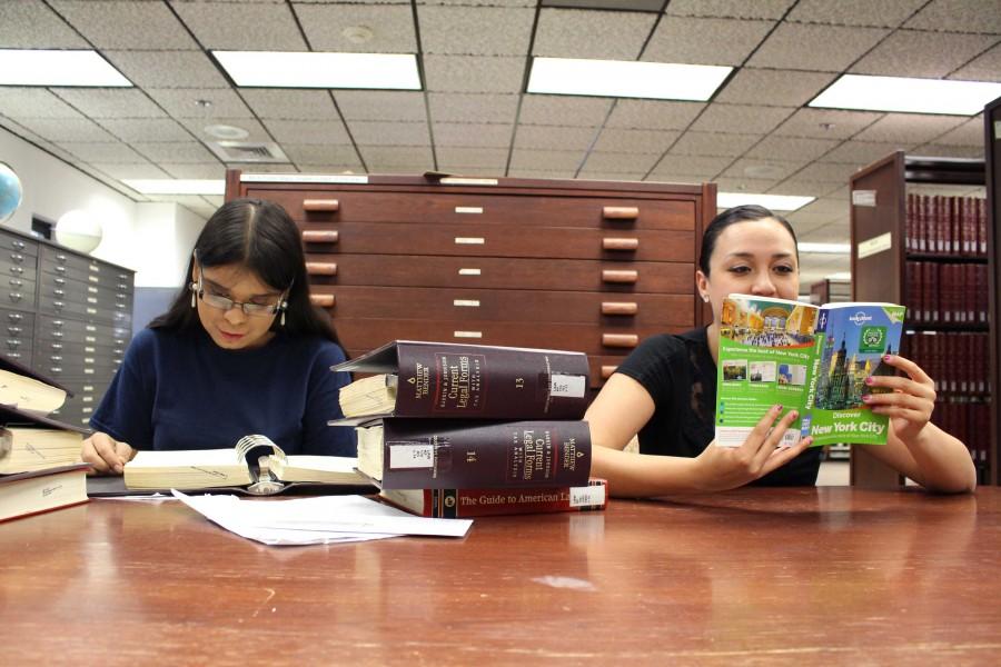 Gloria Almaguer, senior  education major, studies while Bianca Martinez, junior media advertising major, looks over a travel book at the library. 