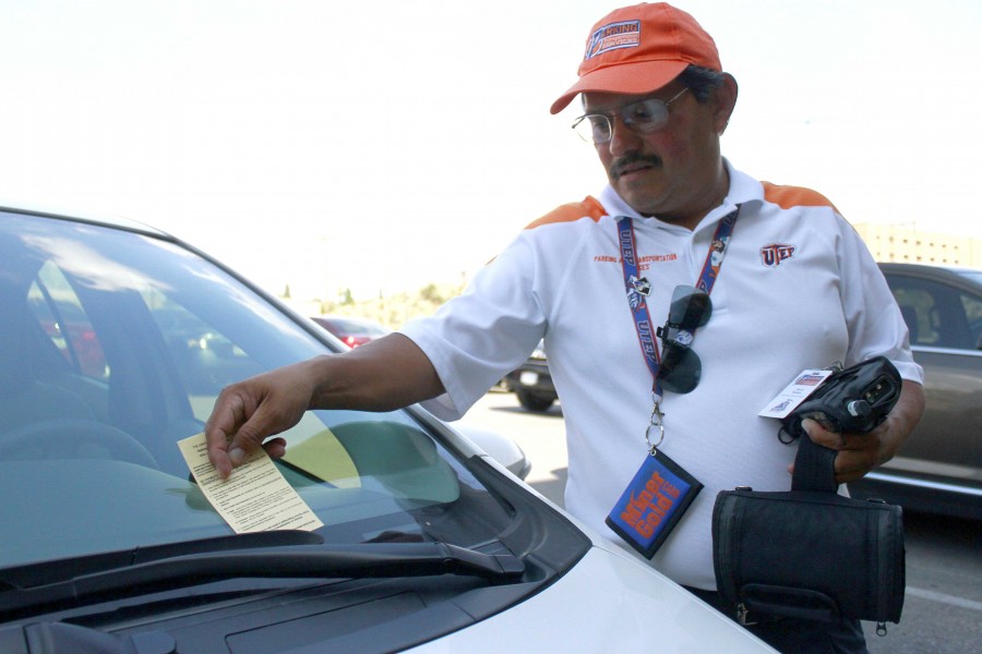 A UTEP Parking and Transportation Services employee places a citation on an illegally parked vehicle.