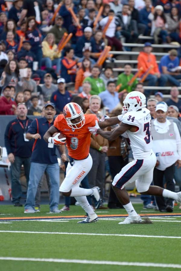 Junior wide receiver Jaquan White stiff arms an FAU defender while running towards the end zone.