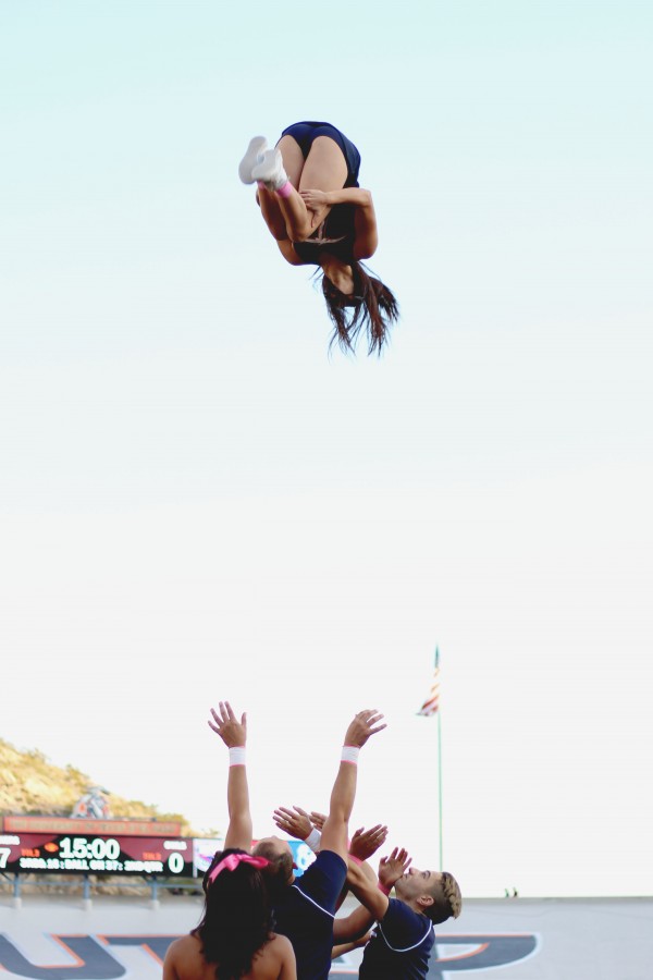 A Miner cheerleader performs a somersault.