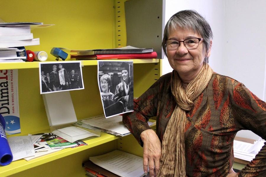 Professor of political science, Kathleen Staudt poses by photos of former students and herself during commencement. 