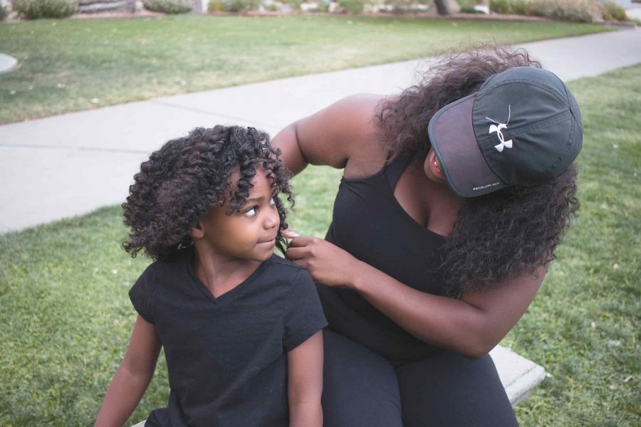 Black Student Union member and senior interdisciplary studies major Tasha Morris-Perez plays with her daughter Kiara’s hair in between shots at their natural hair photo shoot. 