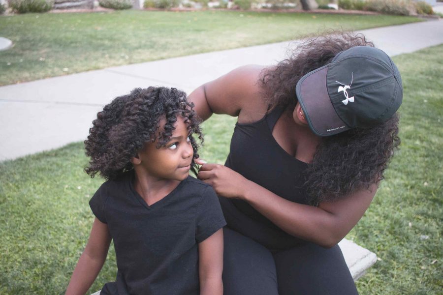 Black Student Union member and senior interdisciplary studies major Tasha Morris-Perez plays with her daughter Kiara’s hair in between shots at their natural hair photo shoot.