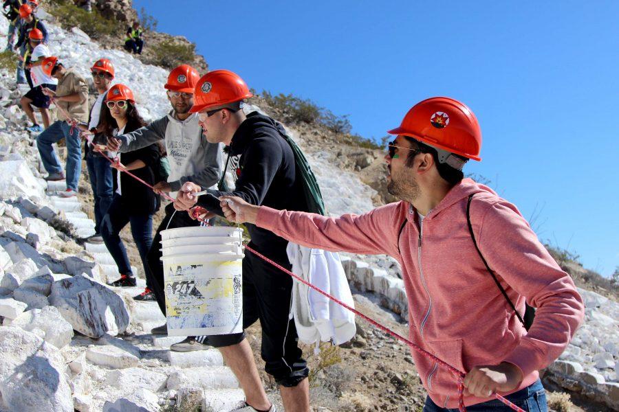 Students work together to passing buckets of paint up to white was the M.