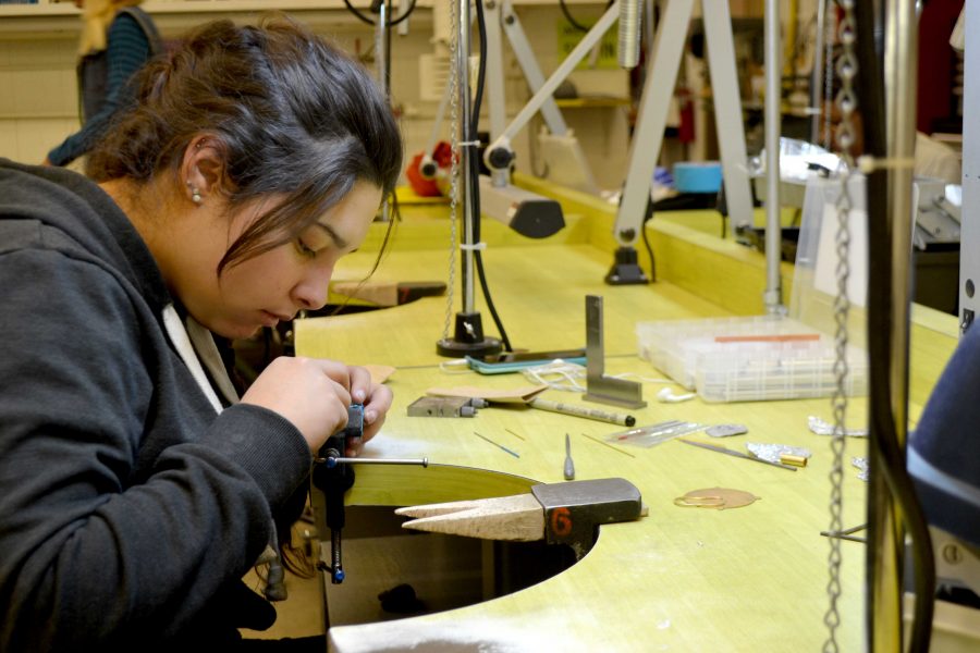 Studio major student works on creating metal jewelry. 