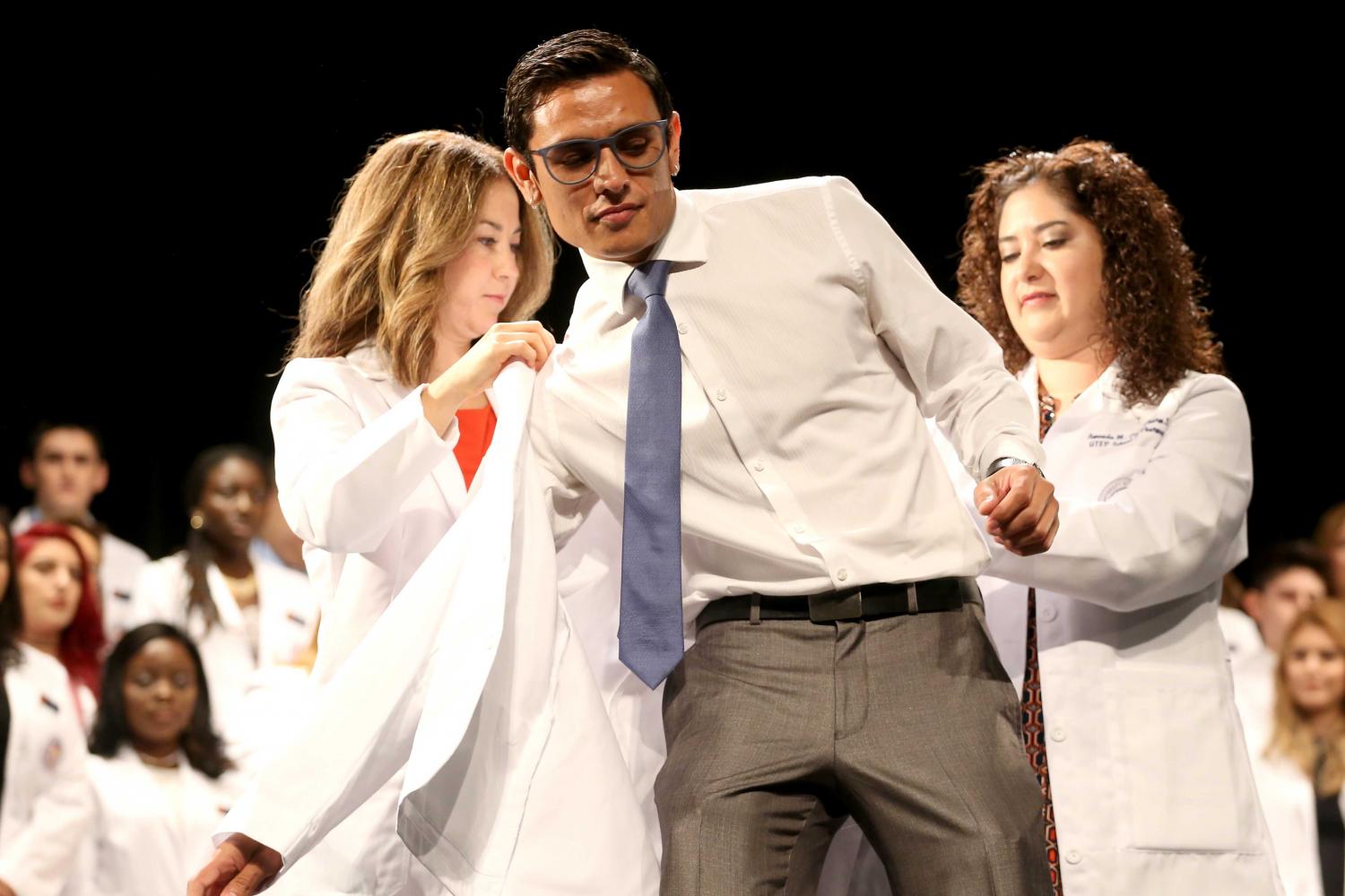 Director of experiential education clinical professor Jacquelyn P. Navarrete and chair of pharmacy practice and clinical sciences clinical professor Amanda M. Loya help students put on coats during the presentation of white coats.