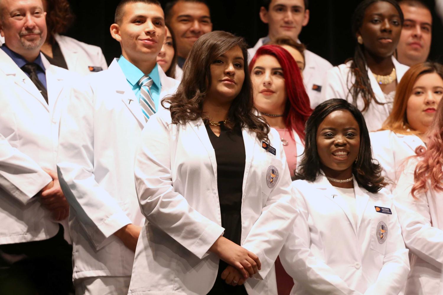 Director of experiential education clinical professor Jacquelyn P. Navarrete and chair of pharmacy practice and clinical sciences clinical professor Amanda M. Loya help students put on coats during the presentation of white coats.