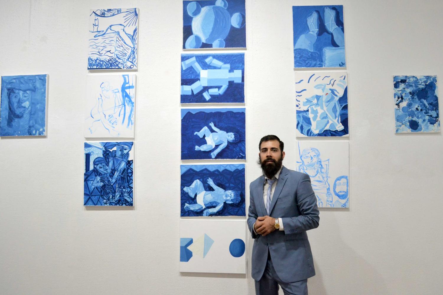 Jorge Alfonso Polanco Aguirre  posing with his paintings at the opening of the exhibit “ The life of J’ on August 5th at the International Museum of Art.