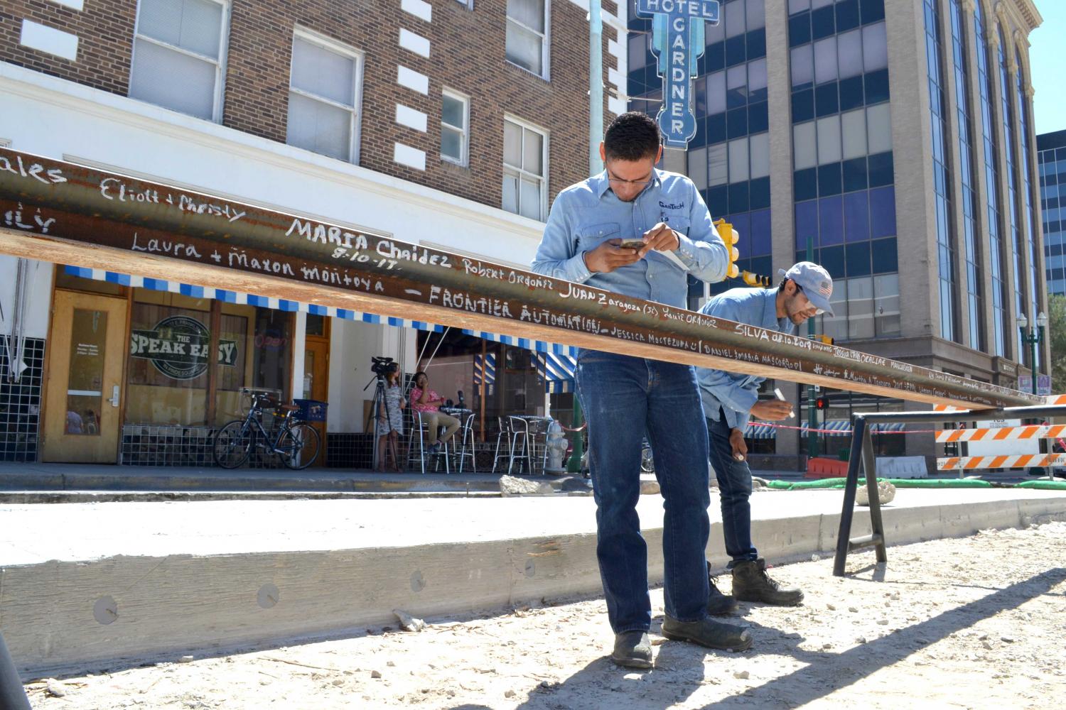 Two men sign their names of the last piece of rail on August 10th at the “Make your Mark: Sign the Last Piece of Rail” event in Downtown El Paso.