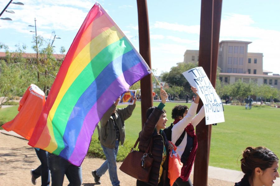 Marching+around+Centennial+Plaza%2C+a+student+holds+a+LGBTQ+flag.+