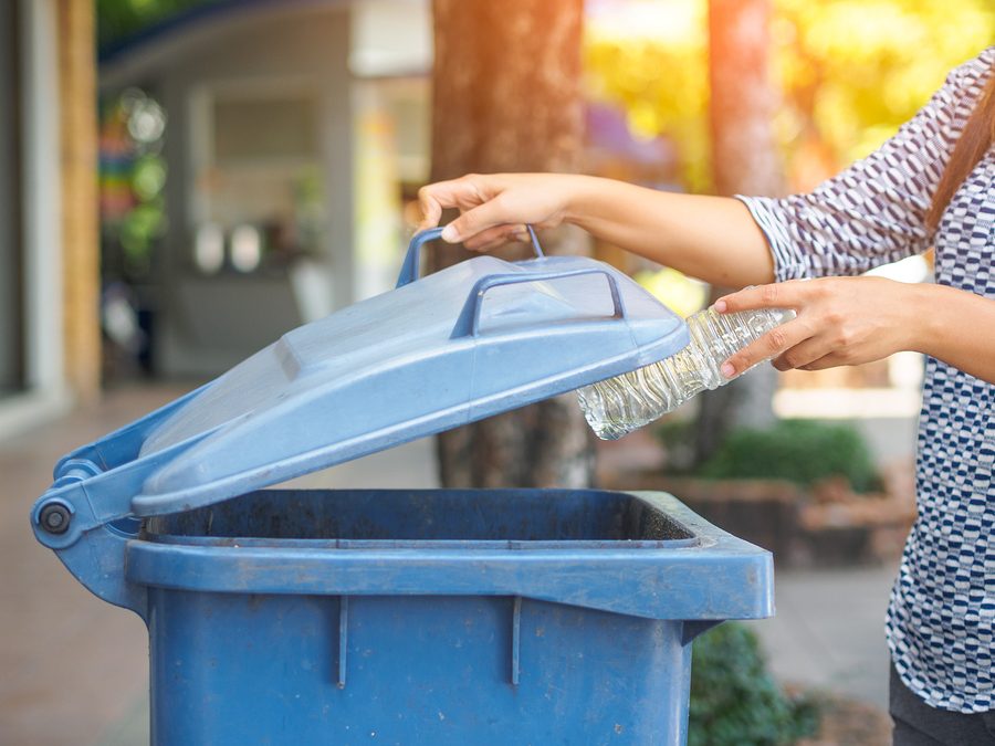 Closeup+portrait+woman+hand+throwing+empty+plastic+water+bottle+in+recycling+bin.