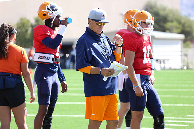 Offensive coordinator Mike Canales goes over the playbook with Kai Locklsey (left) and Calvin Brownholtz (right) camp. 