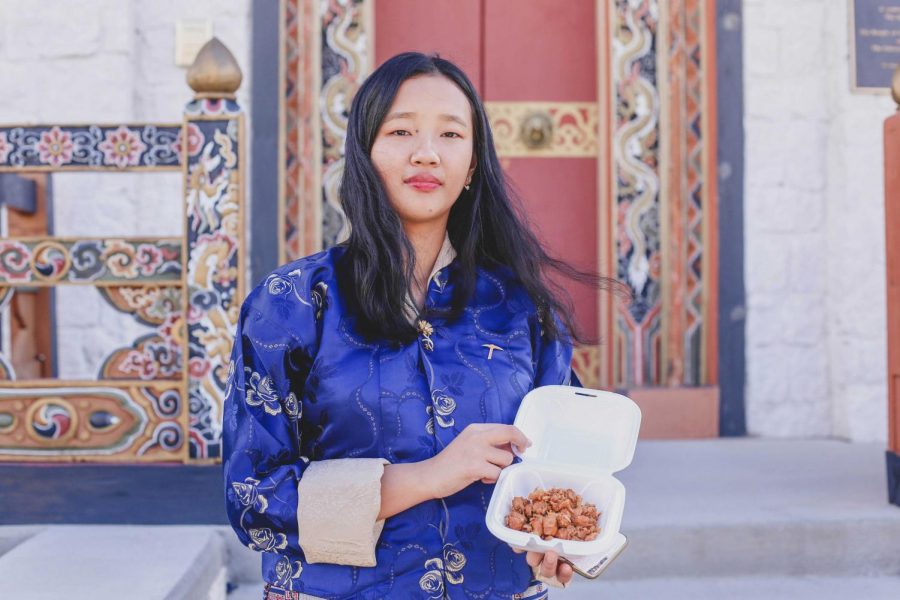Freshman environmental science major Yeshey Seldon poses in front of the Bhutan Temple holding Jasha Maru (Spicy Chicken Curry) sold by the Bhutanese Student Association at the International Food Fair on Monday, Nov. 12. 
