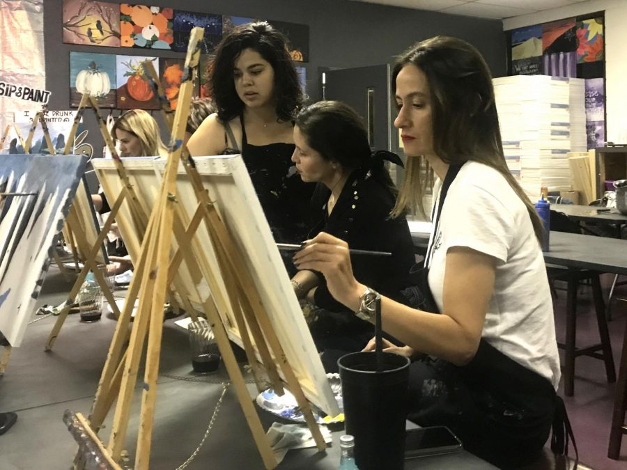 Artist, Ebonie Adame, helps I Painted That! attendees with their “The River Li” paintings Thursday, Oct. 10.