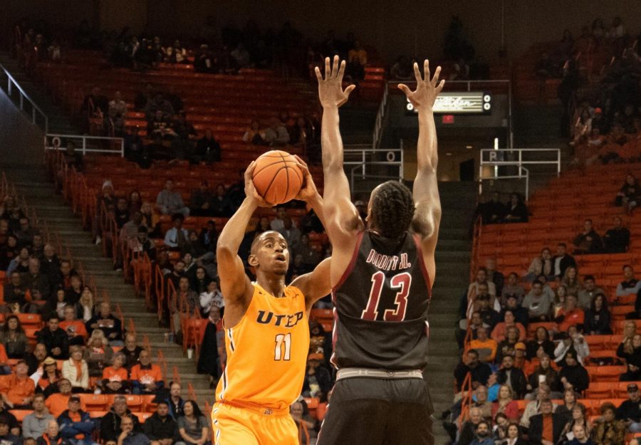 Junior forward Bryson Williams passes the ball over the opposing player while playing against NMSU at the Don Haskins Center.