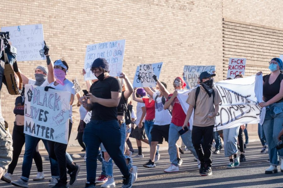 Protesters march pass police station holding signs denouncing police violence against people of color Sunday May 31.