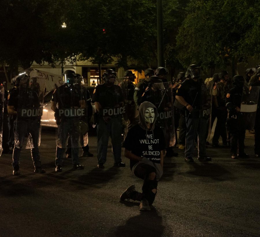 Protester kneels in front of police line on San Antonio Avenue June 2.