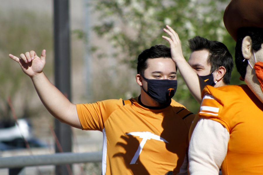 Aaron Edens waves to passing cars on April 7th 2021 in front of the UTEP bookstore 