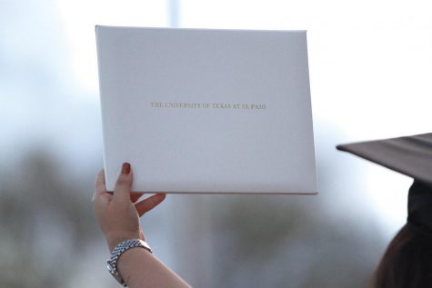 A graduating UTEP student holds a diploma folder given to students when they receive their Masters degree.