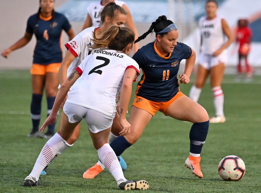 Forward Taya Lopez aims to kick the ball while being surrounded by two defenders. 