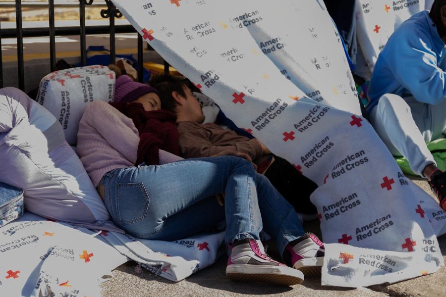 Two people sleep under a makeshift hut made from donated blankets from the American Red Cross Association.  