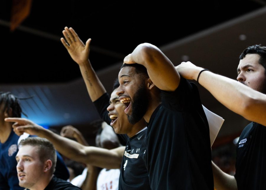 Coaches and players from the sideline celebrate after Tae Hardy dunks a ball.  