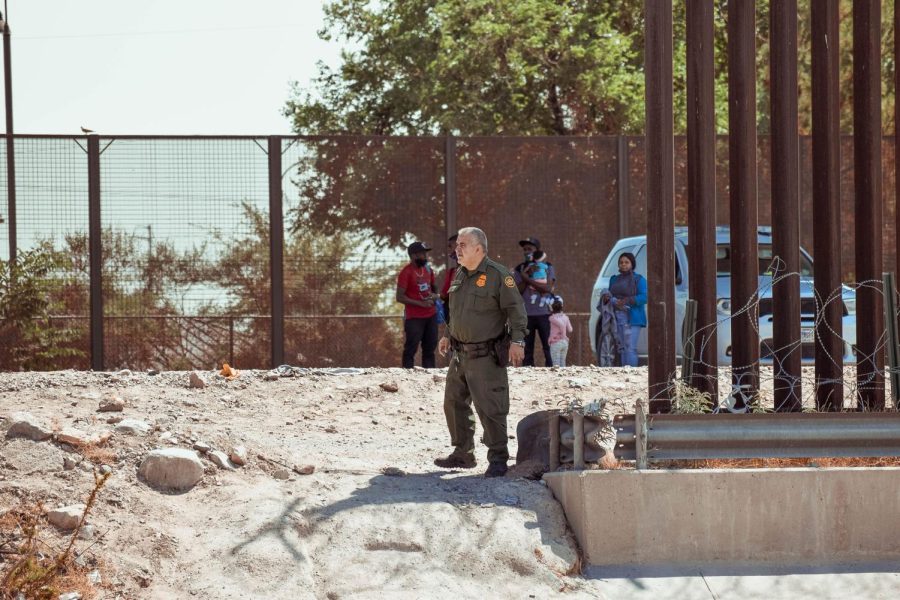 A border patrol agent guards the fence as he receives a group of immigrants from Haiti. 