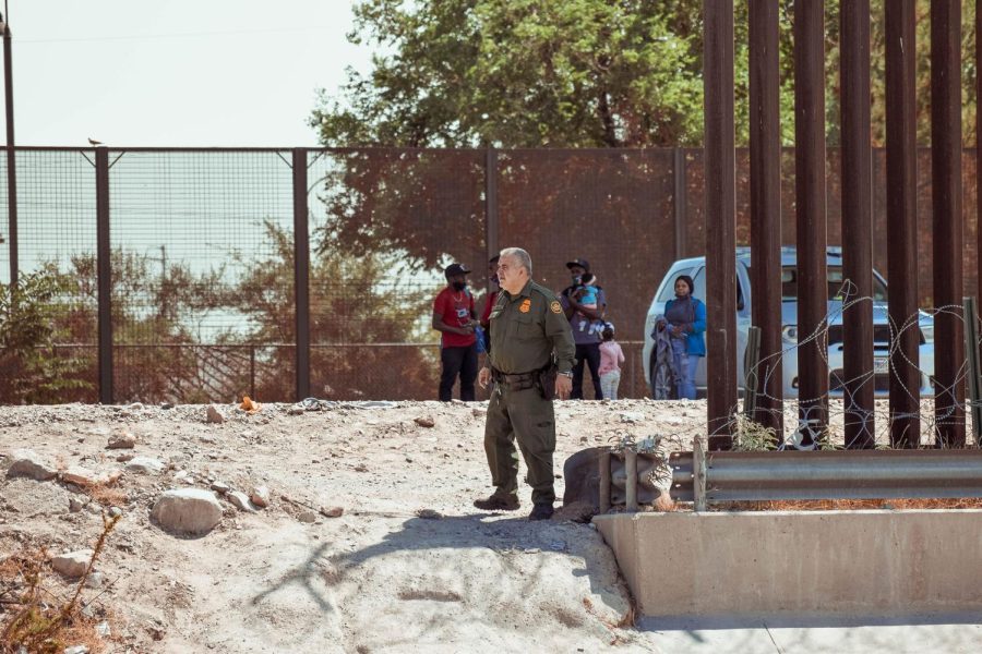A border patrol agent guards the fence as he receives a group of immigrants from Haiti. 