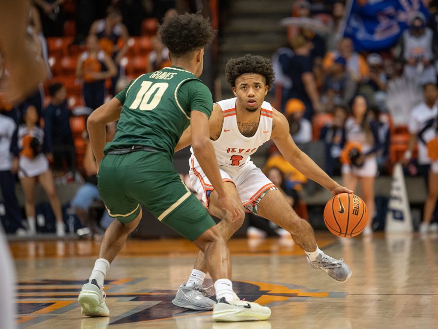 Guard Malik Zachery dribbles the ball while being closely defended. 