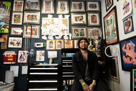 Julio Cesar Pizana Aleman, is an artist at Monolith Tattoo. He sits in front of his wall of designs, which he says each have his own special spin on them. 