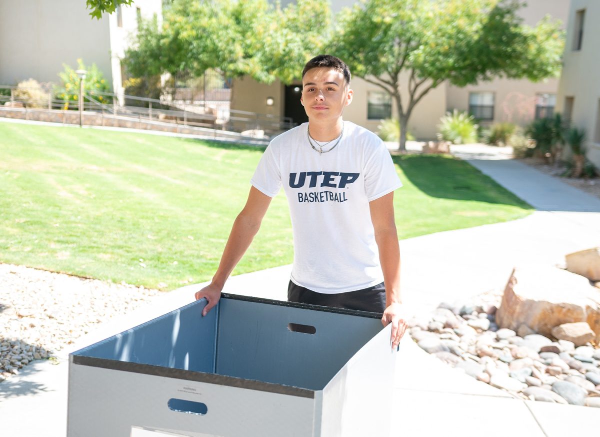 Freshman, Luke Watts, poses for a photo while pushing a moving cart. 