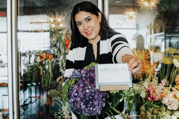 Loni Guillen holds out a bouquet of flowers and a business card. 