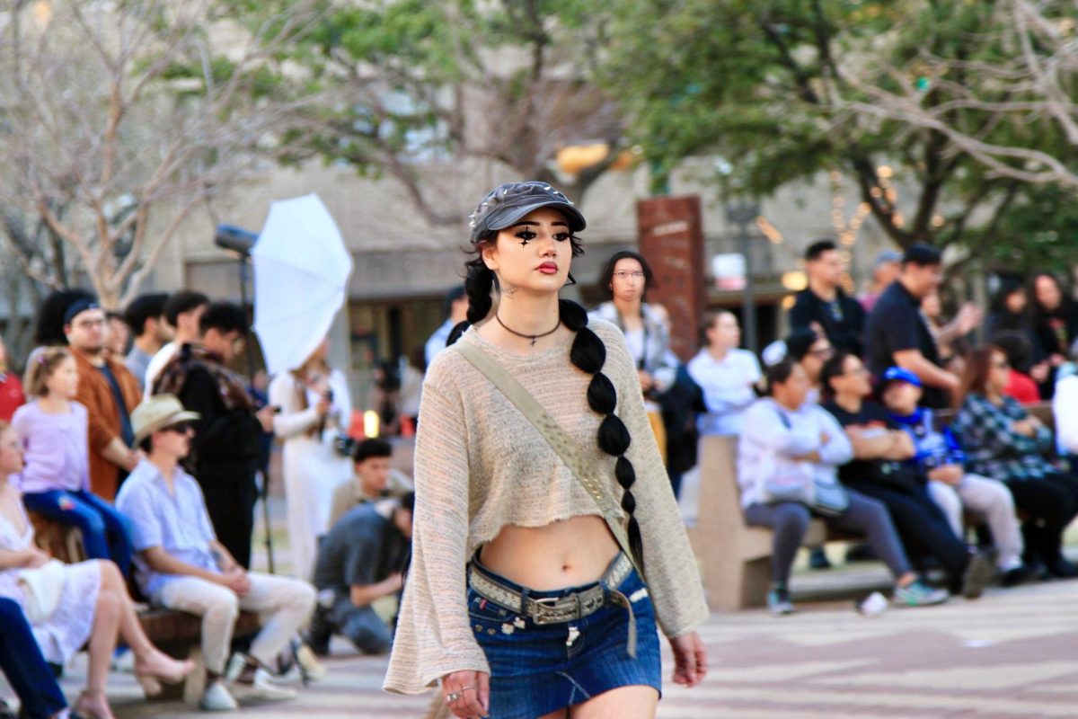 Model for Sergio Estrada wearing a short denim skirt with a loose beige top. Styled with a cross-body bag and spikey accessories.  