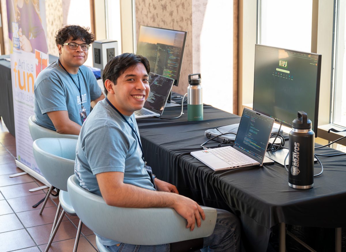 Competitors pose for a photo as they program a game on their computer.