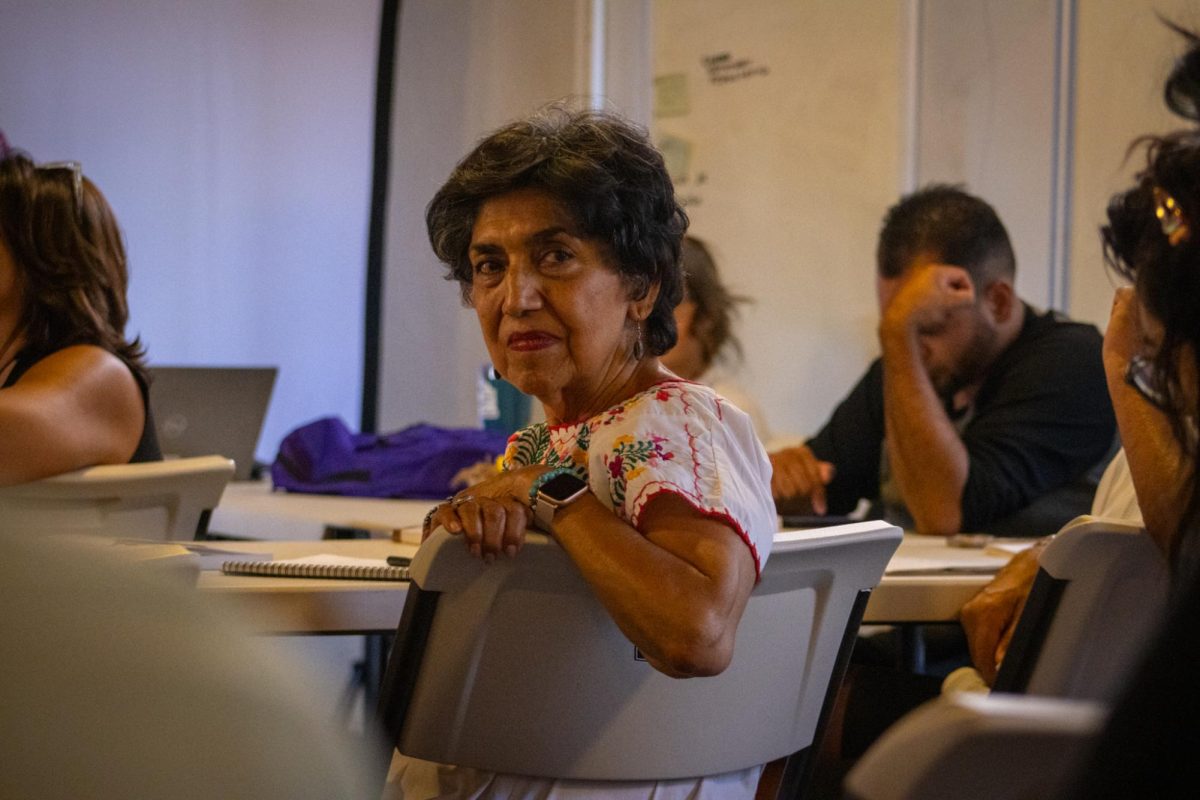 A student listens attentively to the class surrounded by her peers eager
to learn. 