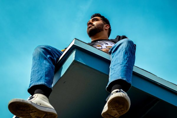 Sports editor Kristian Hernandez recreates the cover of J. Cole’s 2014 Forest Hills Drive by sitting on a rooftop, mirroring the original pose and mood.